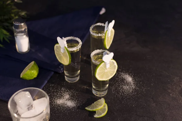 Schnapsgläser aus Gold-Tequila mit einem Rand aus Salz und Limettenscheiben. — Stockfoto
