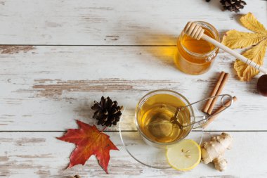 Sonbahar yapraklı, ahşap zemin üzerinde zencefil, limon ve tarçın olan bir fincan sonbahar çayı..