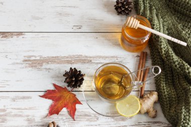 Sonbahar yapraklı, ahşap zemin üzerinde zencefil, limon ve tarçın olan bir fincan sonbahar çayı..