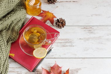 Sonbahar yapraklı, ahşap zemin üzerinde zencefil, limon ve tarçın olan bir fincan sonbahar çayı..