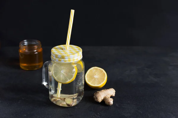 Jengibre con agua de desintoxicación de limón sobre fondo negro . — Foto de Stock