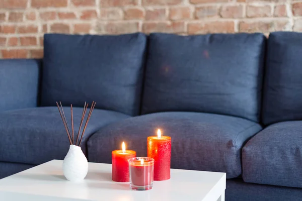 Номер освежающий палочки воздуха и красные горящие свечи на столе на домашний современный интерьер . — стоковое фото