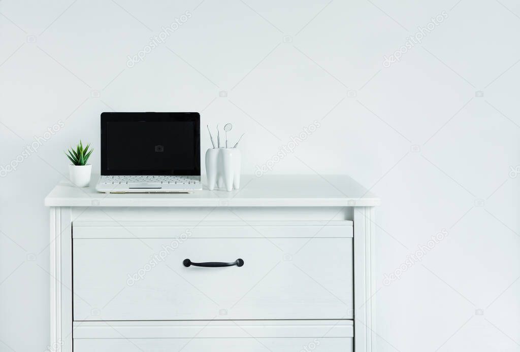 Dentist table with laptop and teeth model. Computer with blank screen on dentist table, template for design.