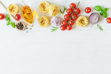 Yemek pişirmek için İtalyan makarna malzemeleri. Çiğ makarna, sebze, baharat ve otlar beyaz ahşap arka planda üstten görünüyor. İtalyan sağlıklı vejetaryen yemekleri.