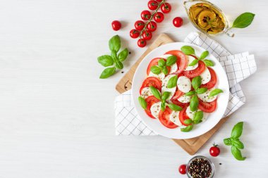 Mozarellalı Caprese salatası, domates, beyaz arka plan manzaralı taze zeytinyağı ve fesleğen. Lezzetli İtalyan vejetaryen salatası.