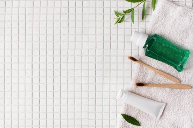 Bambu diş fırçası, diş macunu ve beyaz mozaik arka plan görünümlü dişler için durula. Diş temizliği konsepti. Sürdürülebilir yaşam tarzı.