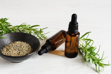 Biberiye yağı ve beyaz ahşap arka planda taze biberiye dalı..