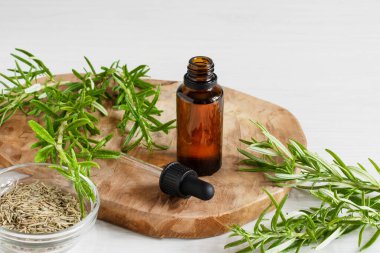 Biberiye yağı ve beyaz ahşap arka planda taze biberiye dalı..