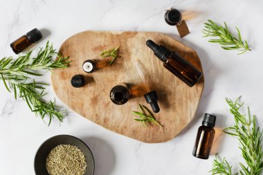 Biberiye yağı şişeleri ve beyaz mermer arka plan görünümlü taze biberiye dalı..