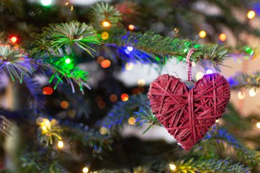 Noel ağacında kırmızı kalp ve parlak renkli bokeh. Noel süsü, kopyalama alanı.