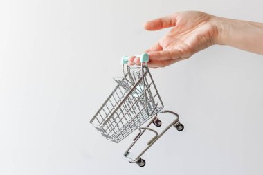 Beyaz arka planda boş oyuncak arabası olan bir kadın. Alışveriş konsepti. Boşluğu kopyala.