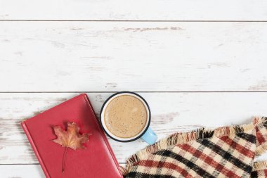Bir fincan kahve, ekose ve beyaz ahşap zemin üzerine kitap. Sonbahar bileşimi. 