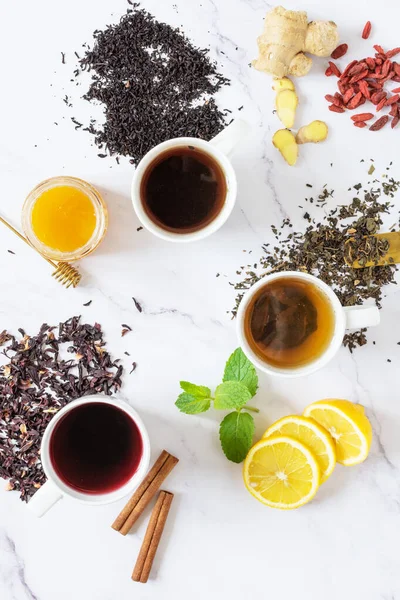 Green, black and red tea in a white ceramic cups top view. Different tea drink and ingredients top view.