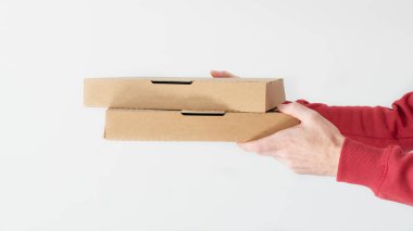 Karton pizza kutularını beyaz arka planda tutan kurye elleri. Yemek dağıtım servisi..