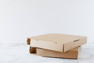 Masanın üzerinde beyaz arkaplanda fotokopi alanı olan karton pizza kutuları. Pizza teslimat servisi..