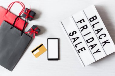 Siyah Cuma mesajlı ışık kutusu, çevrimiçi alışveriş tasarımı için boş akıllı telefon ve beyaz arkaplanda üst görünümü sunar. Kara Cuma gününde online alışveriş.