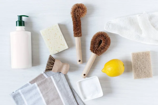 Eco friendly bamboo dish brushes and lemon with baking soda for cleaning top view on white wooden background. Zero waste concept. Plastic and chemistry free.