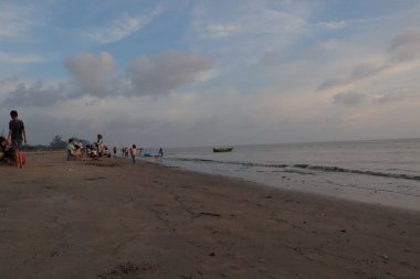 Sakin okyanusun üzerinde gün batımı suyun üzerine sıcak bir parıltı saçıyor. Gökyüzünün altındaki kumlu plaj turuncu ve pembe renkler mavi denize karışıyor.. 