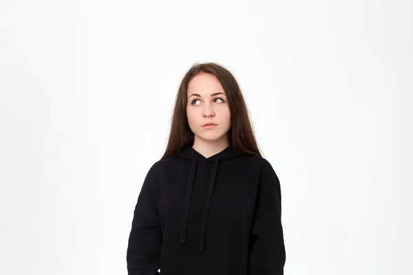 Portrait of a pretty young woman in a black sweatshirt standing infront of white background — Stock Photo, Image