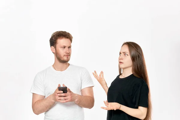 Studiová střela mladého páru hádání. Žena je rozrušená, že člověk pořád používá telefon, aniž by věnoval pozornost jejímu. — Stock fotografie