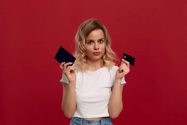 V-işareti ile zafer jest ifade kırmızı bir arka plan üzerinde dans beyaz bir t-shirt kıvırcık sarı saçlı bir kızın portresi. Model kameraya gülümsüyor ve pasaport tutar.