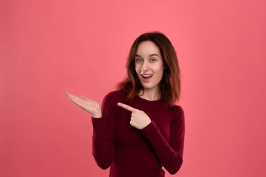 Heyecanlı genç bayan ayakta koyu pembe arka plan üzerinde bir el bir avuç ile sizin ihtiyatlı tutmak için hazır izole