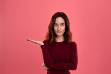 Heyecanlı genç bayan ayakta koyu pembe arka plan üzerinde bir el bir avuç ile sizin ihtiyatlı tutmak için hazır izole