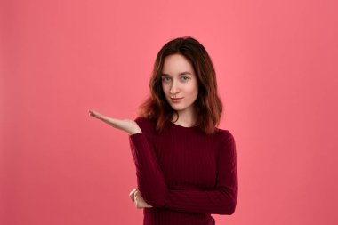 Heyecanlı genç bayan ayakta koyu pembe arka plan üzerinde bir el bir avuç ile sizin ihtiyatlı tutmak için hazır izole