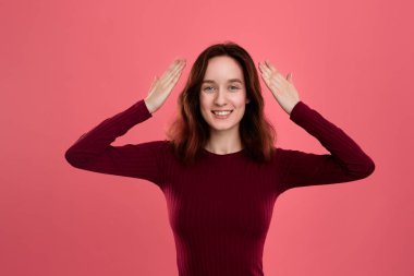 Şaşırtıcı genç bayan ayakta karanlık pembe arka plan üzerinde saklanma gibi eller AJU el yukarıda tutan avuç içinde izole