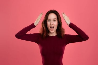 Şaşırtıcı genç bayan ayakta karanlık pembe arka plan üzerinde saklanma gibi eller AJU el yukarıda tutan avuç içinde izole