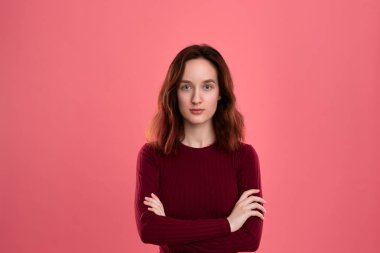 Koyu pembe bir arka planda ayakta güzel bir esmer kız portre. Model üzerinde silah ile kamera bakıyor. 