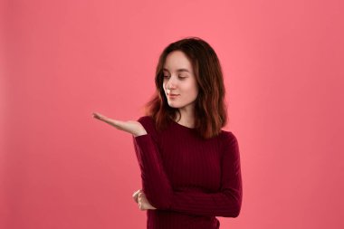 Heyecanlı genç bayan ayakta koyu pembe arka plan üzerinde bir el bir avuç ile sizin ihtiyatlı tutmak için hazır izole
