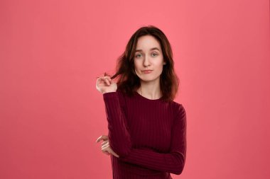 Koyu pembe bir arka plan üzerinde duran güzel bir esmer kız Portresi. Model bir coquet bir rüya gibi bir görünüm ile saç bukleler görünüyor. 