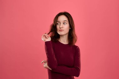 Koyu pembe bir arka plan üzerinde duran güzel bir esmer kız Portresi. Model bir coquet bir rüya gibi bir görünüm ile saç bukleler görünüyor. 