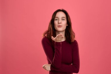 Romantik el öpücük gönderirken koyu pembe arka plan üzerinde izole ayakta Mutlu genç bayan. 