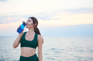 Kablosuz kulaklık ve akıllı saatler sabah egzersiz içme suyu sonra dinlenme ile genç esmer kadın.
