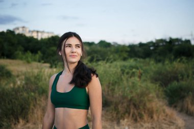 Güzel esmer kadın gün doğumunda deniz kıyısında mornong koşu sonra dinleniyor müzik dinlerken.