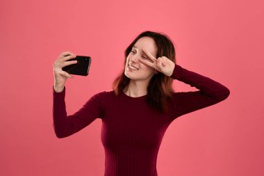 Bir cep telefonu ile selfie yapan güzel bir genç esmer kadın fotoğrafı 