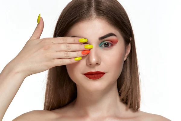 Ritratto ravvicinato di bella giovane donna con trucco a colori brillante che si tiene per mano con manicure luminosa vicino al viso — Foto Stock