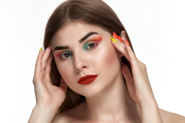 Ritratto ravvicinato di bella giovane donna con trucco a colori brillante che si tiene per mano con manicure luminosa vicino al viso — Foto Stock