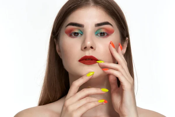 Ritratto ravvicinato di bella giovane donna con trucco a colori brillante che si tiene per mano con manicure luminosa vicino al viso — Foto Stock