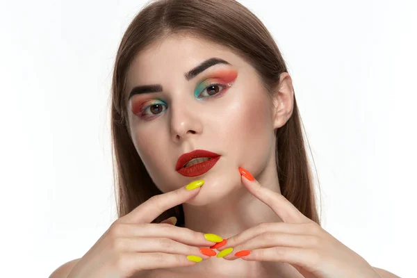 Ritratto ravvicinato di bella giovane donna con trucco a colori brillante che si tiene per mano con manicure luminosa vicino al viso — Foto Stock