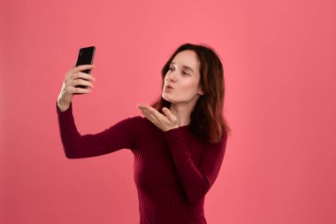 Bir cep telefonu ile selfie yapan güzel bir genç esmer kadın fotoğrafı.