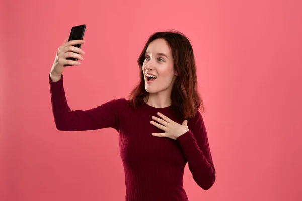 Foto de uma jovem morena bonita fazendo selfie com um telefone celular . — Fotografia de Stock