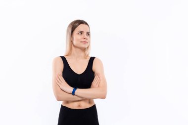 Nabzı ölçen akıllı saatli siyah spor giyimli genç sportif sarışın kadın beyaz arka plan üzerinde duran elleri çapraz tutmak.