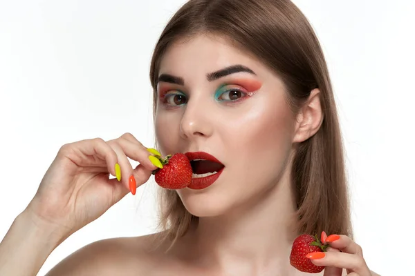 Closeup portré egy gyönyörű fiatal nő, élénk színű make-up gazdaság eper az arc közelében. — Stock Fotó