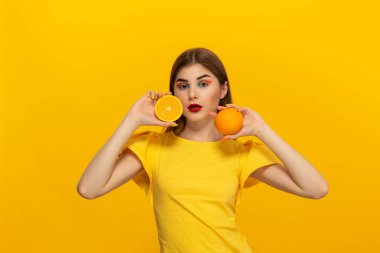 Sarı tee genç model sarı arka plan üzerinde ayakta portakal tutar.