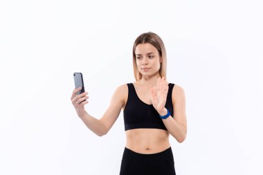 Siyah spor giyimli genç sportif sarışın kadın beyaz arka plan üzerinde duran egzersiz sonrası akıllı telefon ile selfie yapma.