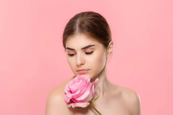 Retrato de cerca de una hermosa joven con rosa rosa aislada sobre fondo rosa . — Foto de Stock