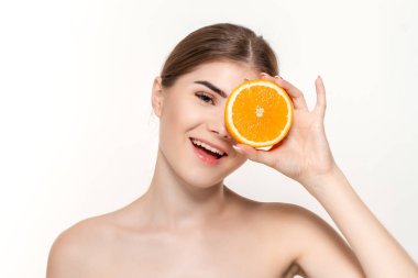 Beyaz arka plan üzerinde izole yüz yakın portakal yarısını tutan mutlu bir güzel genç kız yakın çekim portre.